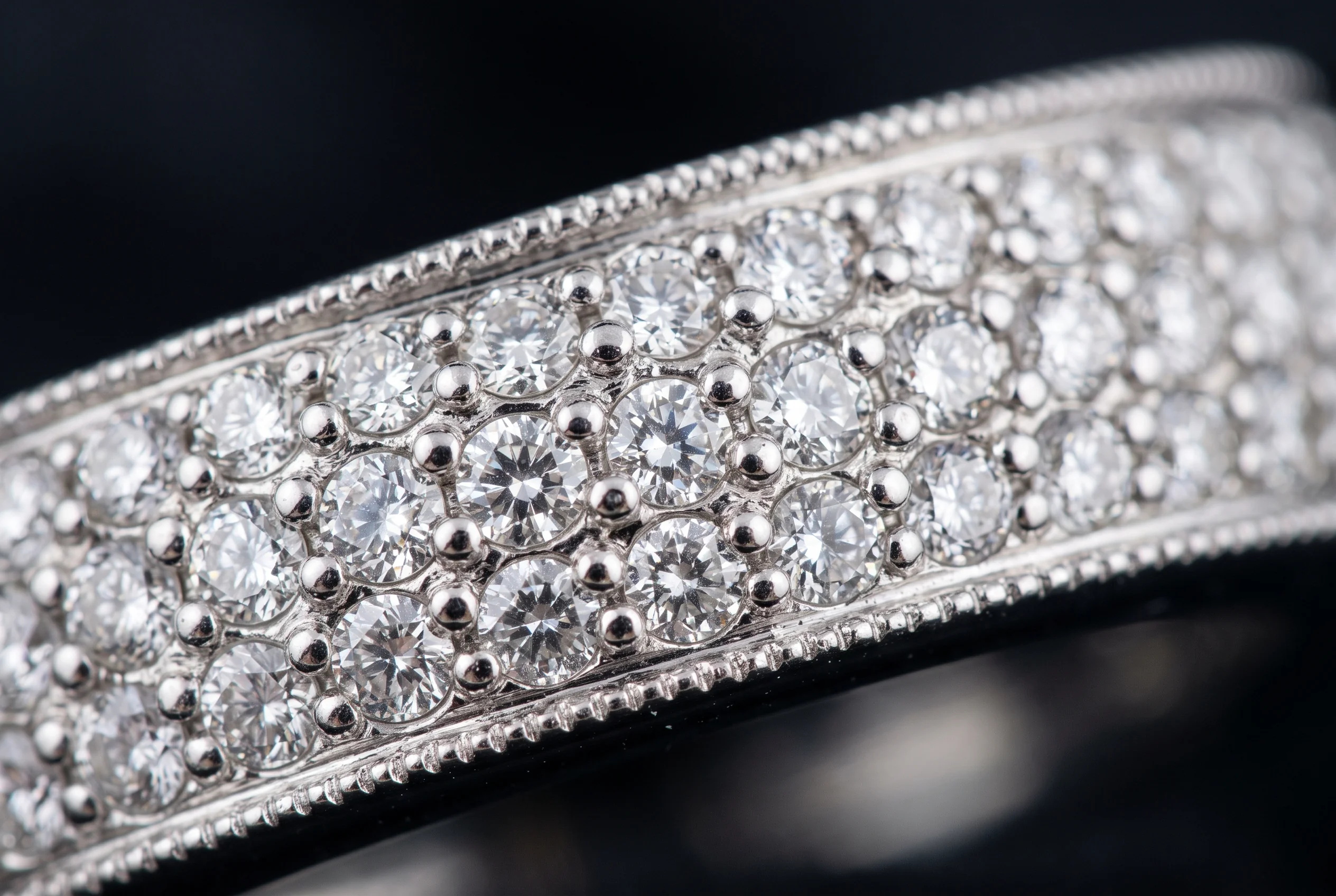 Extreme macro of a pave set band showing tiny diamonds held by fine metal bead grains