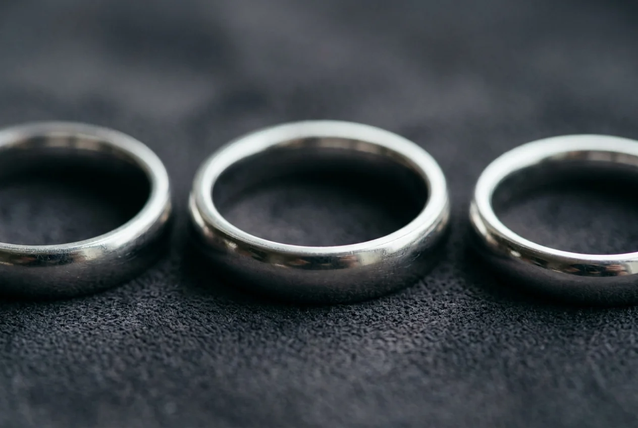 Three plain platinum bands in a row on dark grey suede