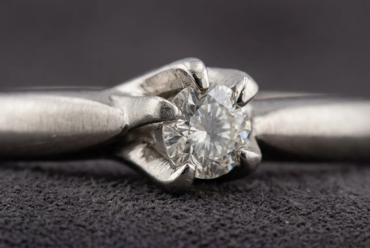 Macro view of worn prongs holding a diamond in a white metal head